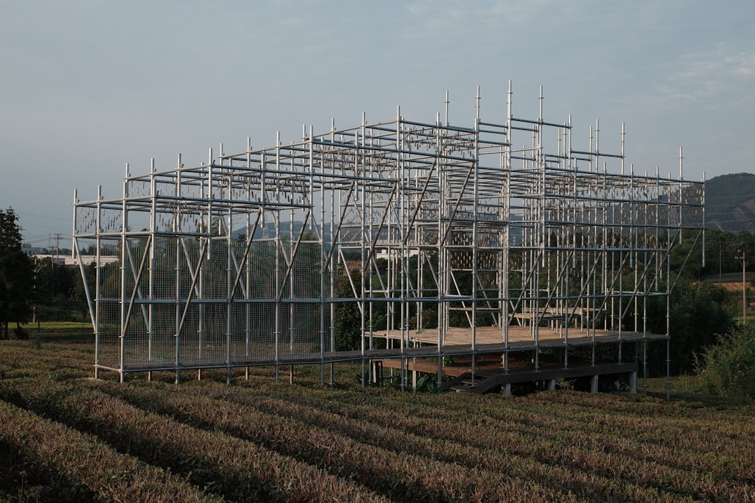 Side-by-side comparison photo of modular home modules being craned onto a foundation versus stick framing on a jobsite