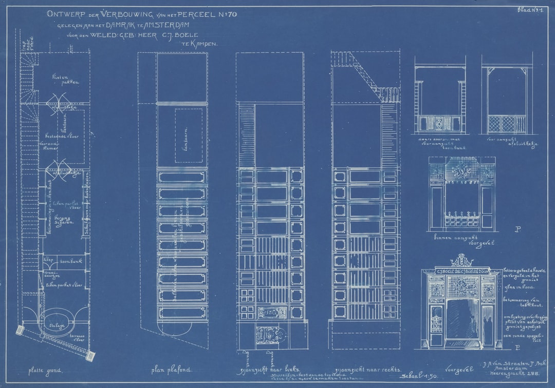 A permit fee schedule and plan review checklist on a desk with blueprints and a calculator
